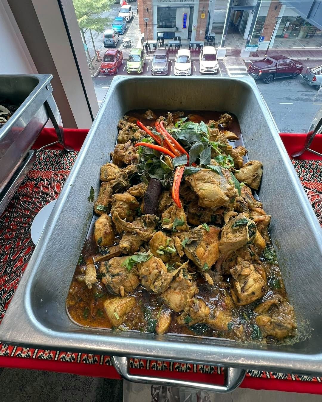 Ayam masak merah in a chafing dish on a songket table runner