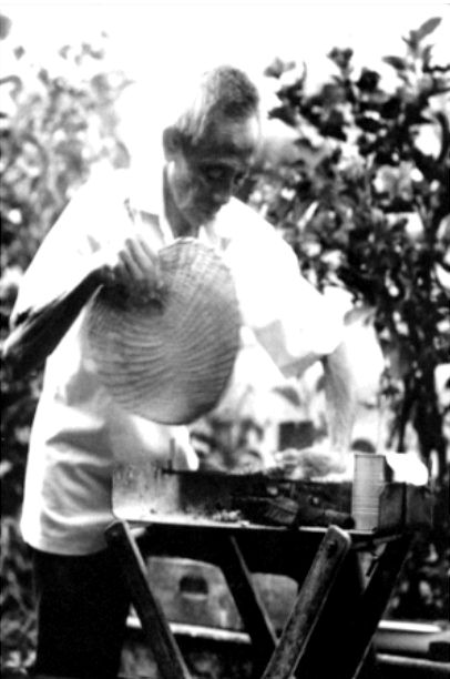 Archival photo of grandfather Suut Bin Hassan fanning the charcoal at his satay stall